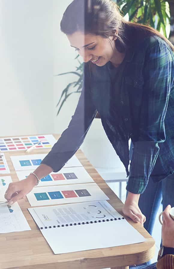 woman leaning over a desk with many papers designing a custom sales training program