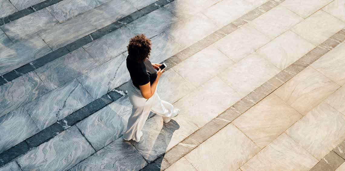 young female sales manager walking confidently down a path with a cell phone confident in the direction she is taking in managing her team's pipeline