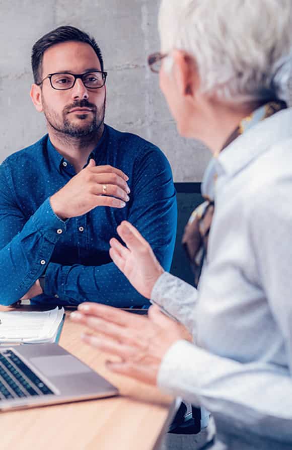 male sales leader in a formal office setting having a difficult yet productive performance conversation with a seller using the framework outlined in the vital conversations manager training module.