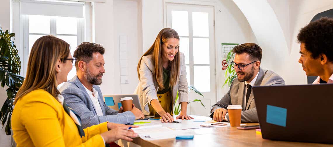sales manager hosting a team meeting at a conference table using the competencies she has developed through her organizations sales manager competency framework