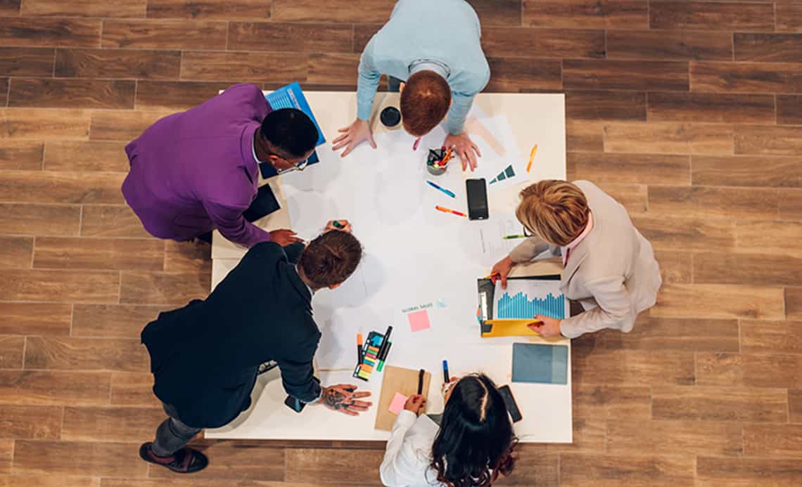 overhead image of a high-performing sales enablement team working together at a table in a modern office