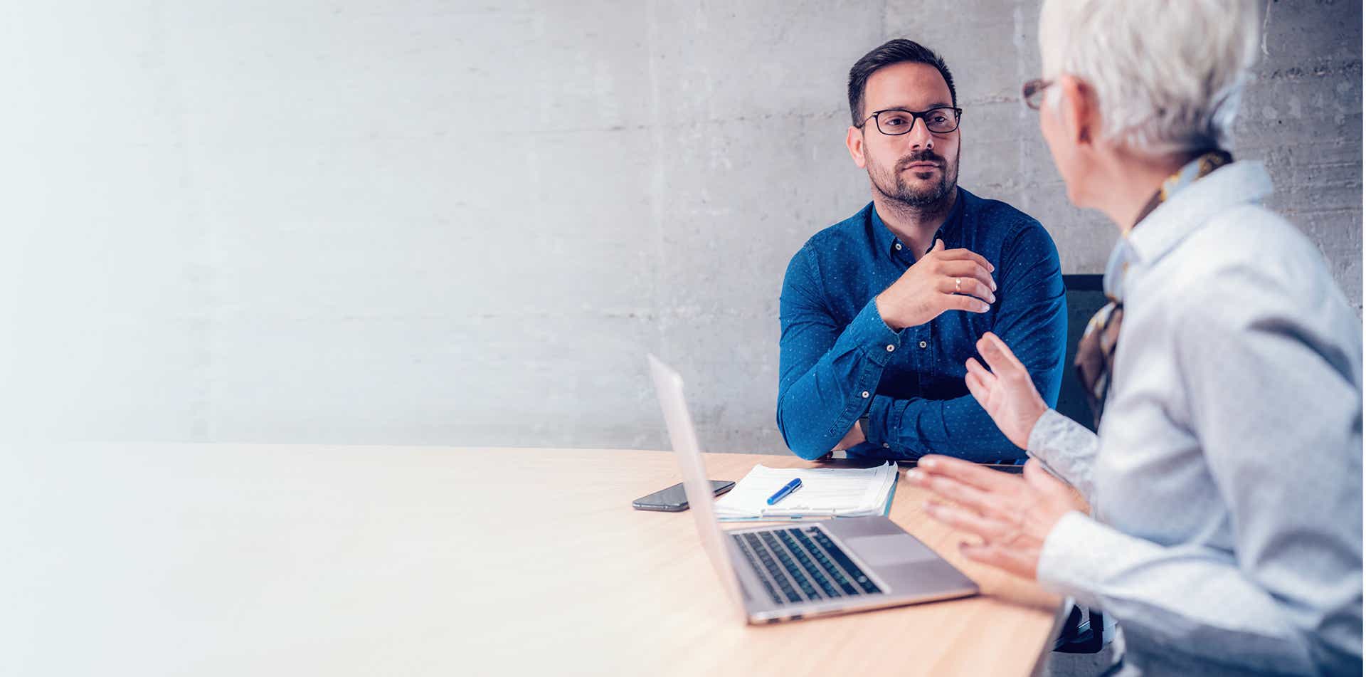 male sales leader in a formal office setting having a difficult yet productive performance conversation with a seller using the framework outlined in the vital conversations manager training module.