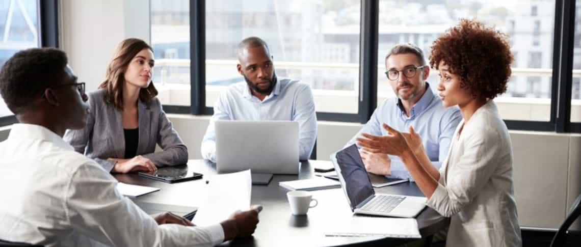 A group of sales colleagues discussing work together at a table