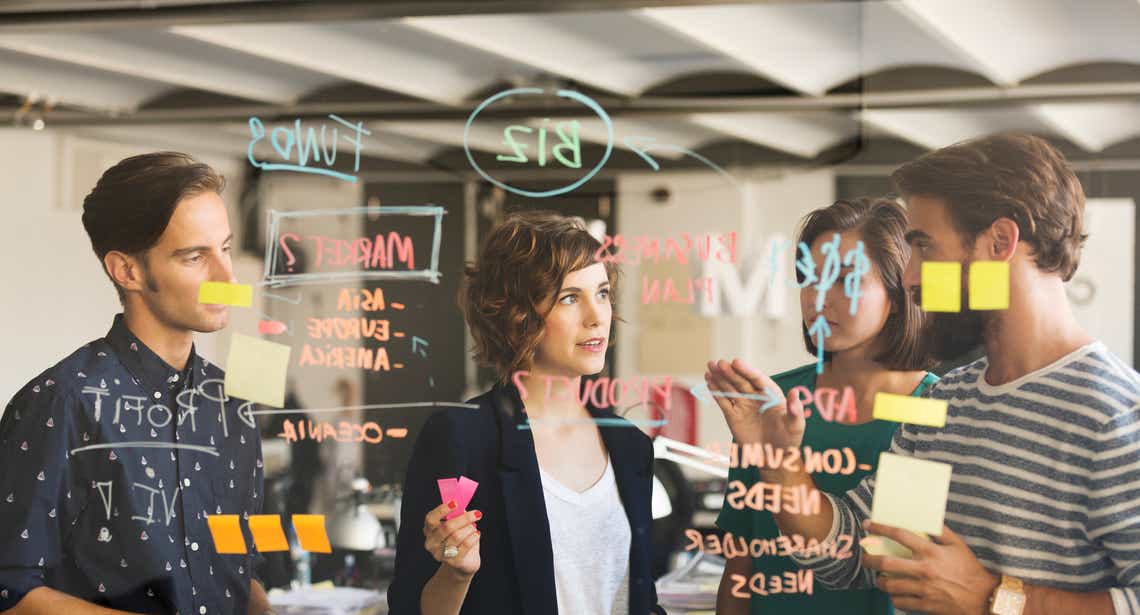 team of young sales leaders determining how to build a sales methodology that works for their team on a clear white board