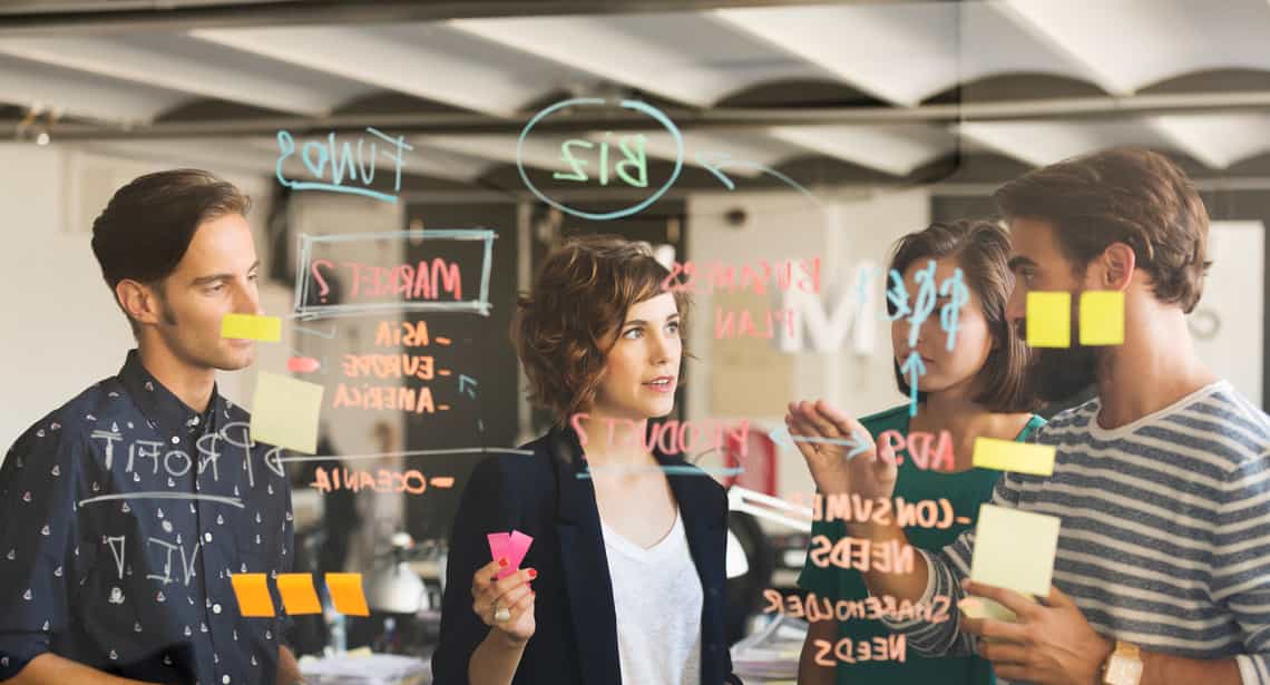 team of young sales leaders determining how to build a sales methodology that works for their team on a clear white board