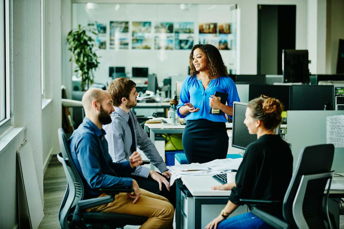 A sales manager addresses their team of three sales professionals helping to reinforce best practices learned in training to drive lasting behavior change.