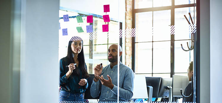 two sales enablement professionals outlining their sales enablement framework on a white board with post-its 