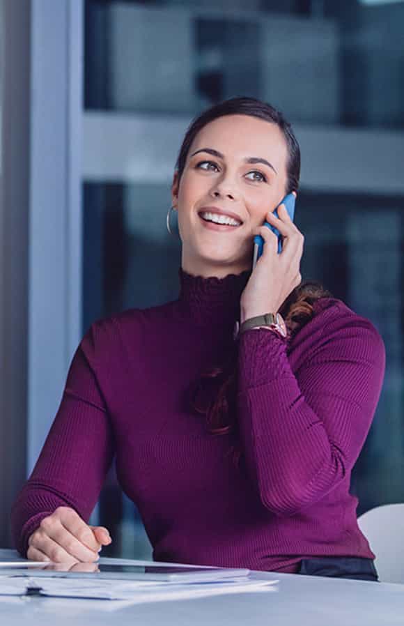 young sales professional sitting at her desk on the phone with a client using the consultative selling skills she learned in richardson's training program