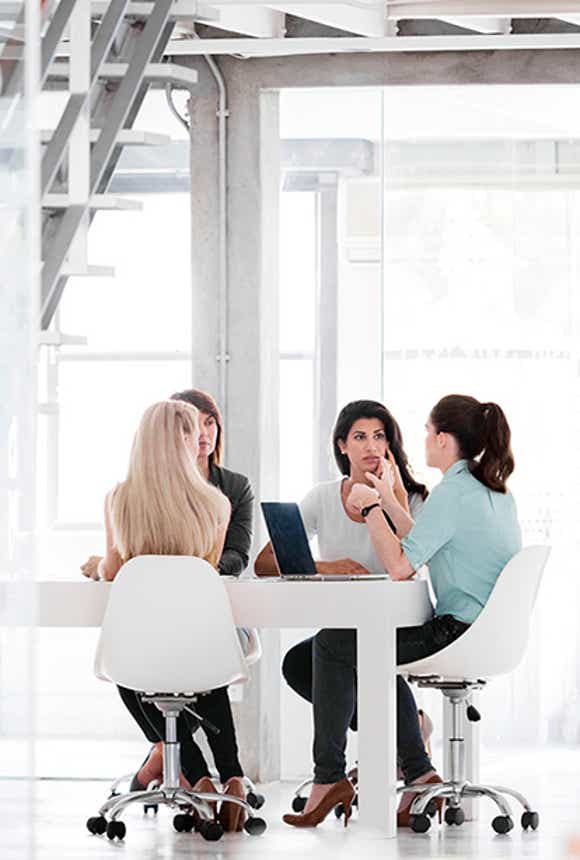 sales leader talking to her team in a bright modern corporate space. She is effectively engaging them in a conversation that will improve their performance by using her agile sales management capabilities.