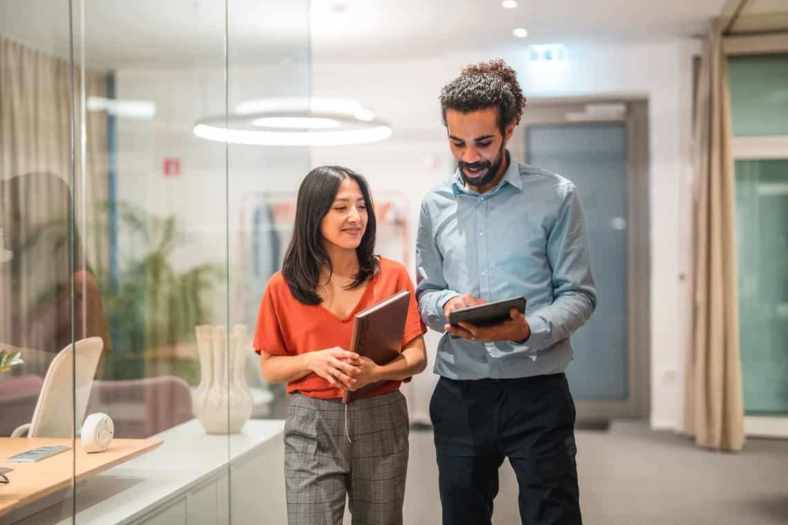 Two colleagues reviewing information together on a tablet in a bright office