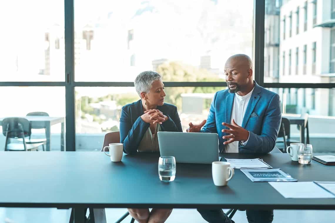 A sales leader and a seller reviewing information together on a laptop