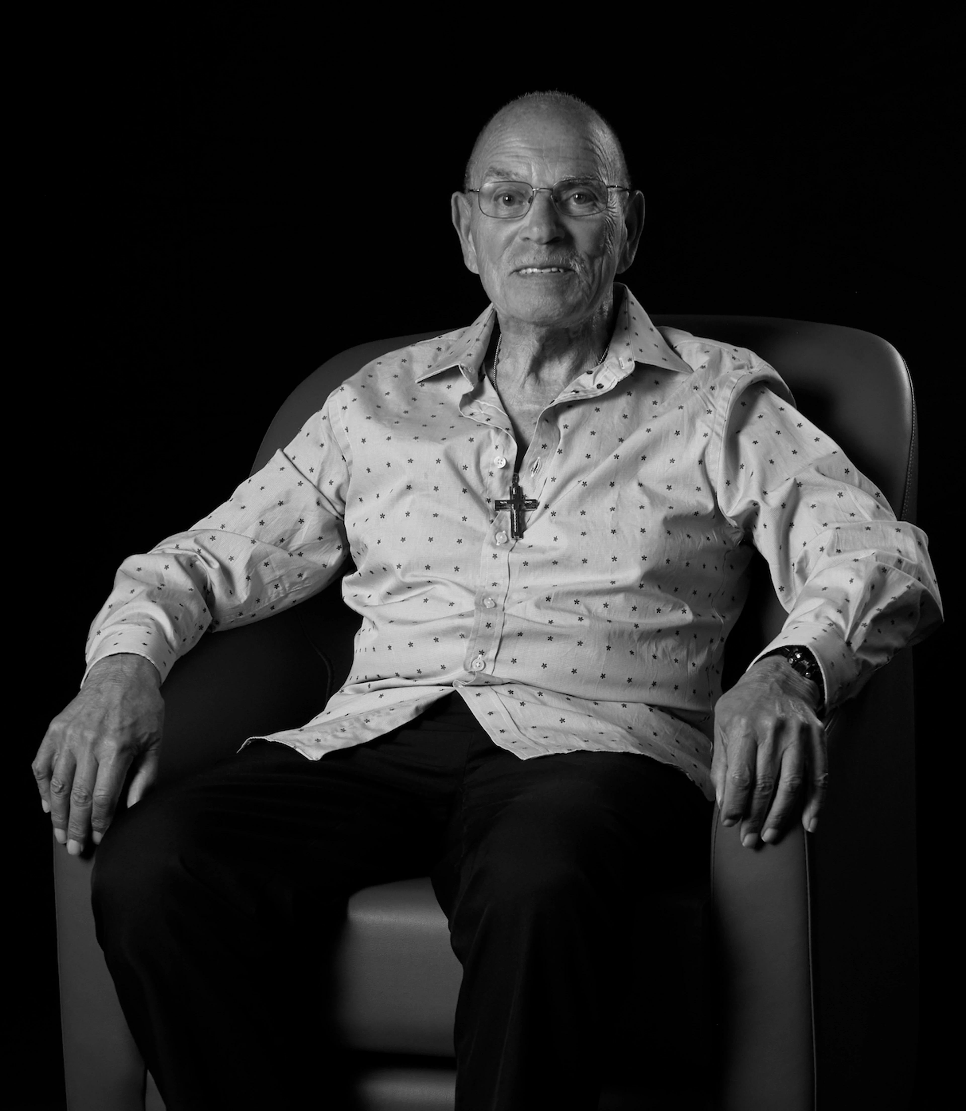 Photo of Gus K sitting in an armchair.