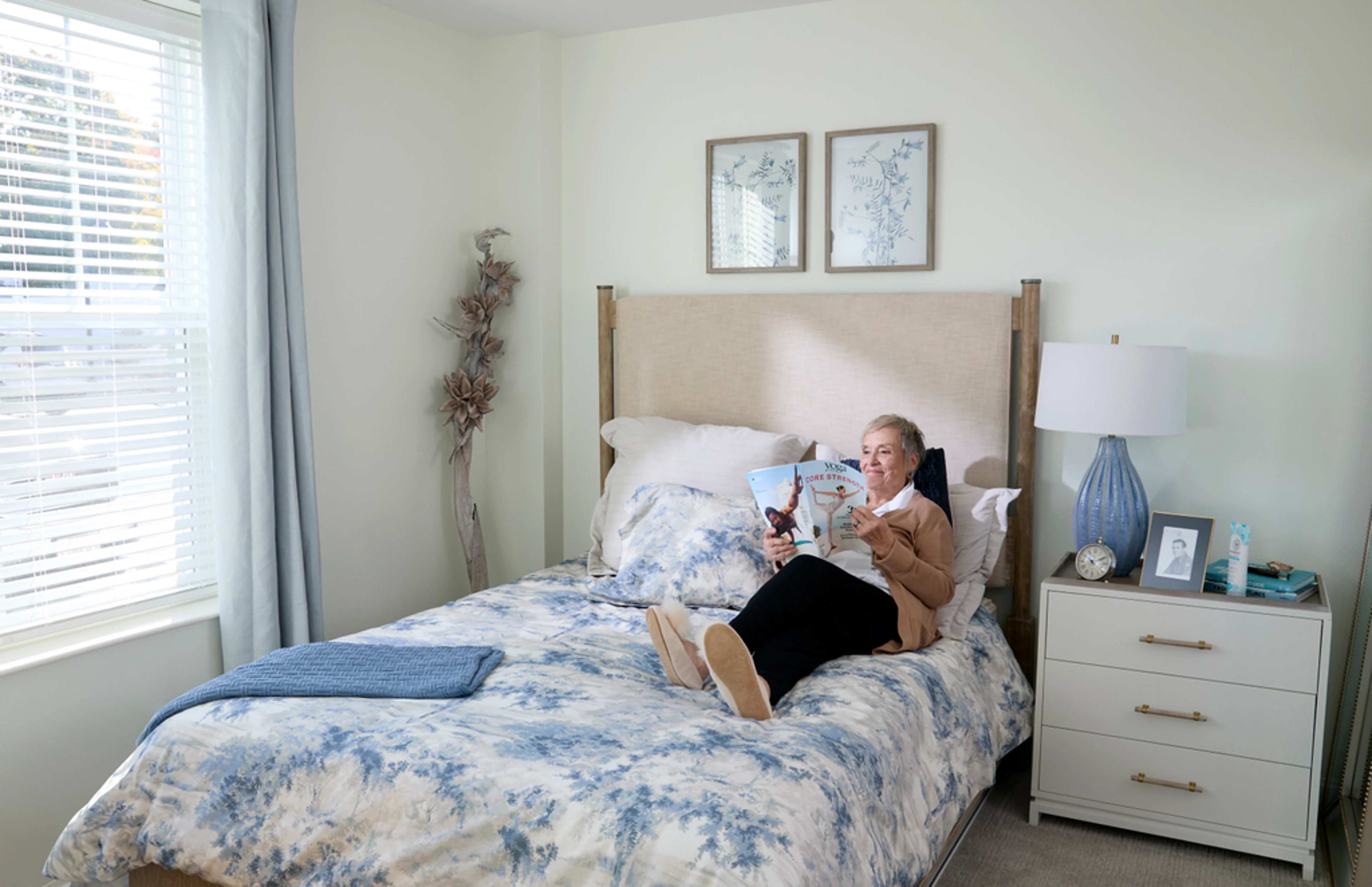 A senior woman laying on a bed reading