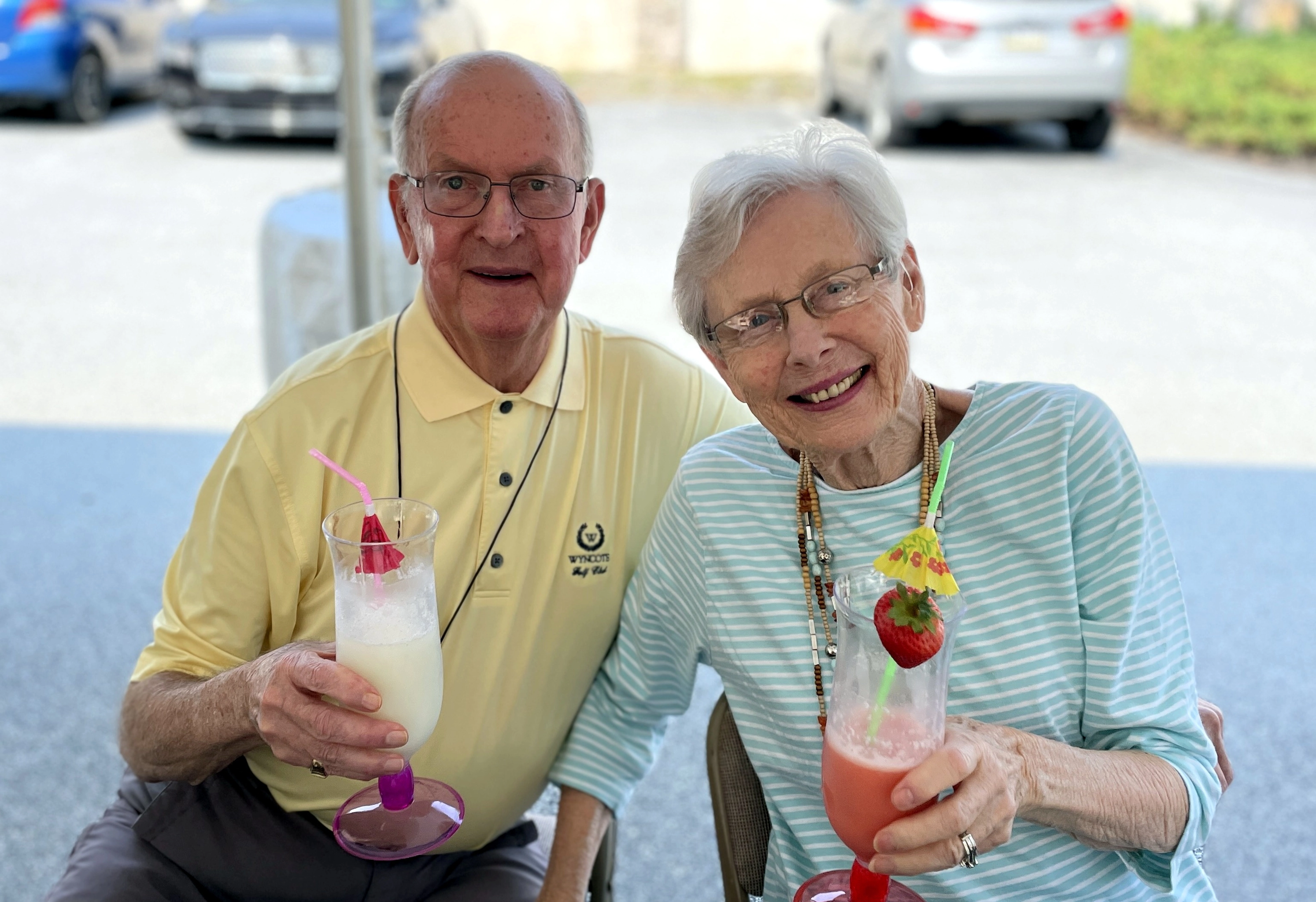 A senior couple smiling holding drinks