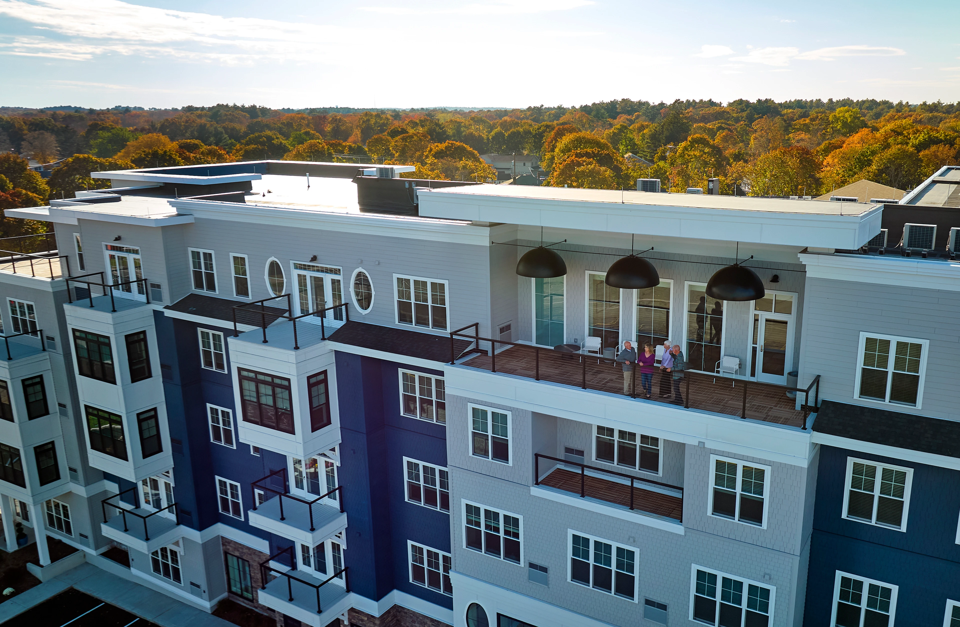 A view of Monarch South Shore from above with four people standing on the fifth floor terrace.