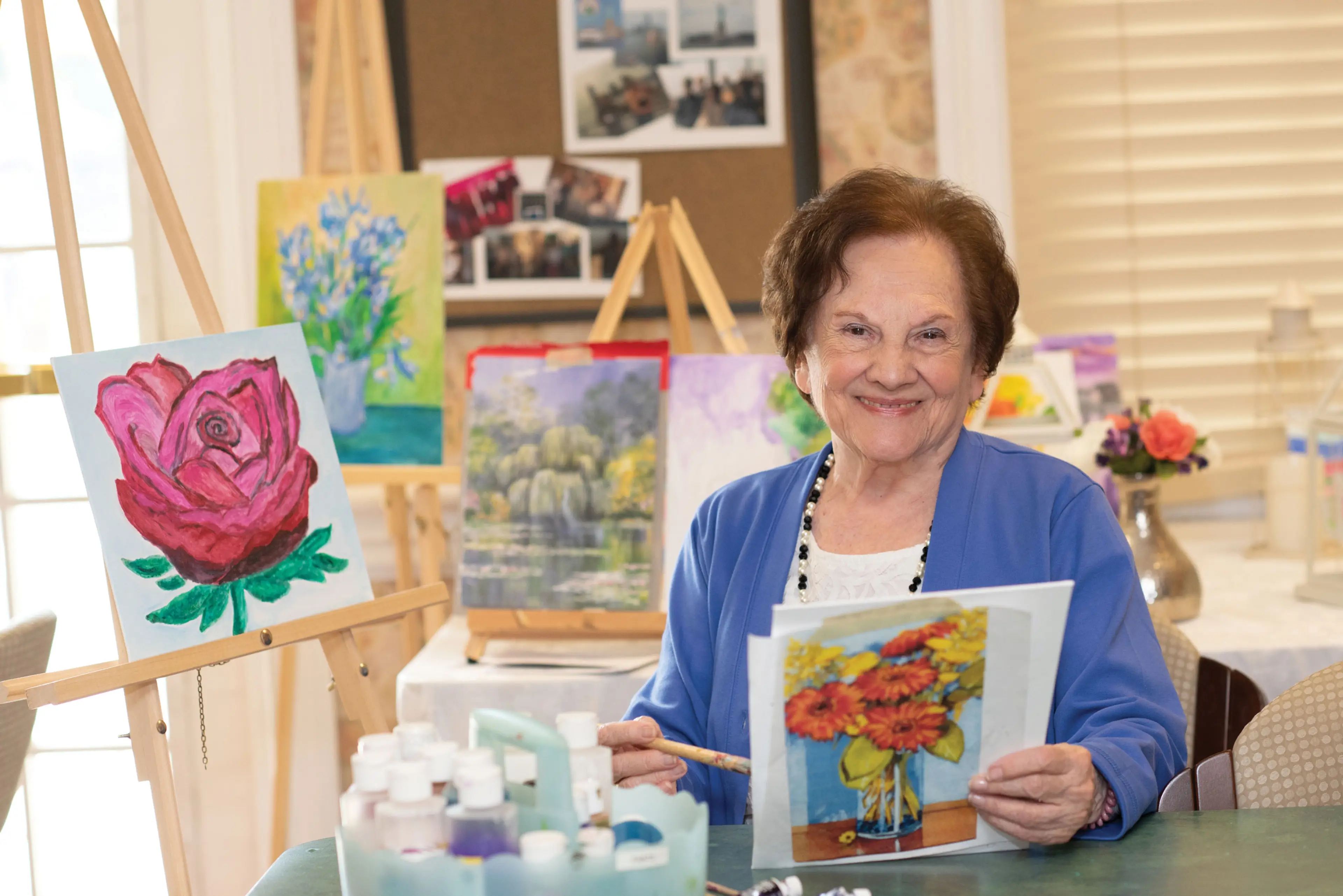 A resident in art class with paintings on easels
