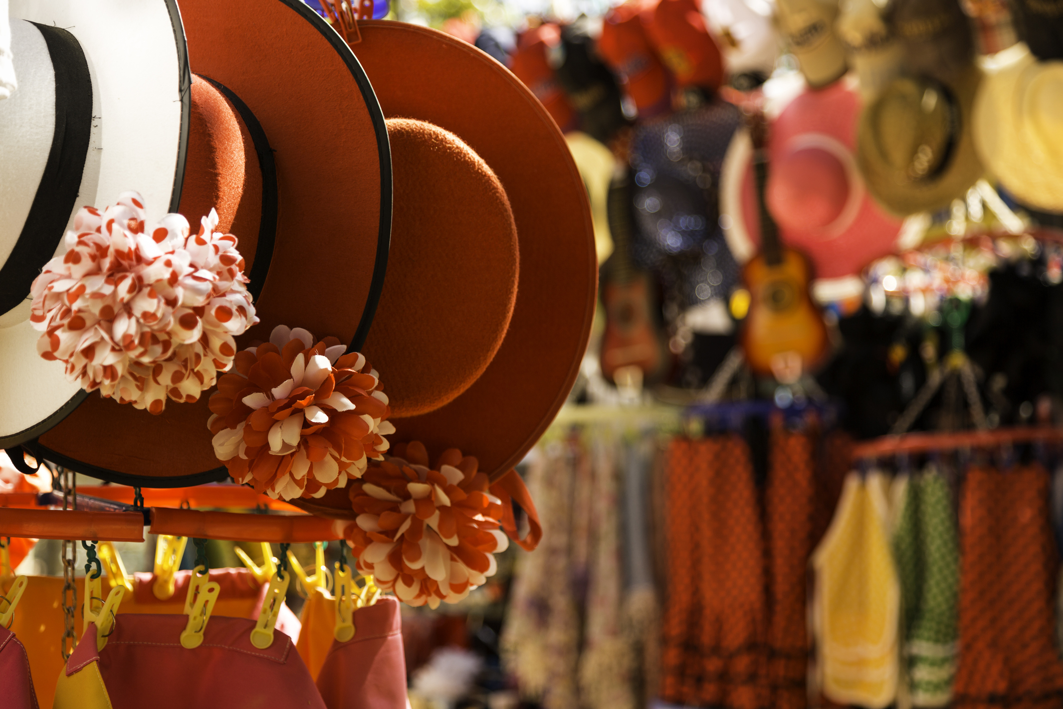 Many hats and clothes hanging in a store.