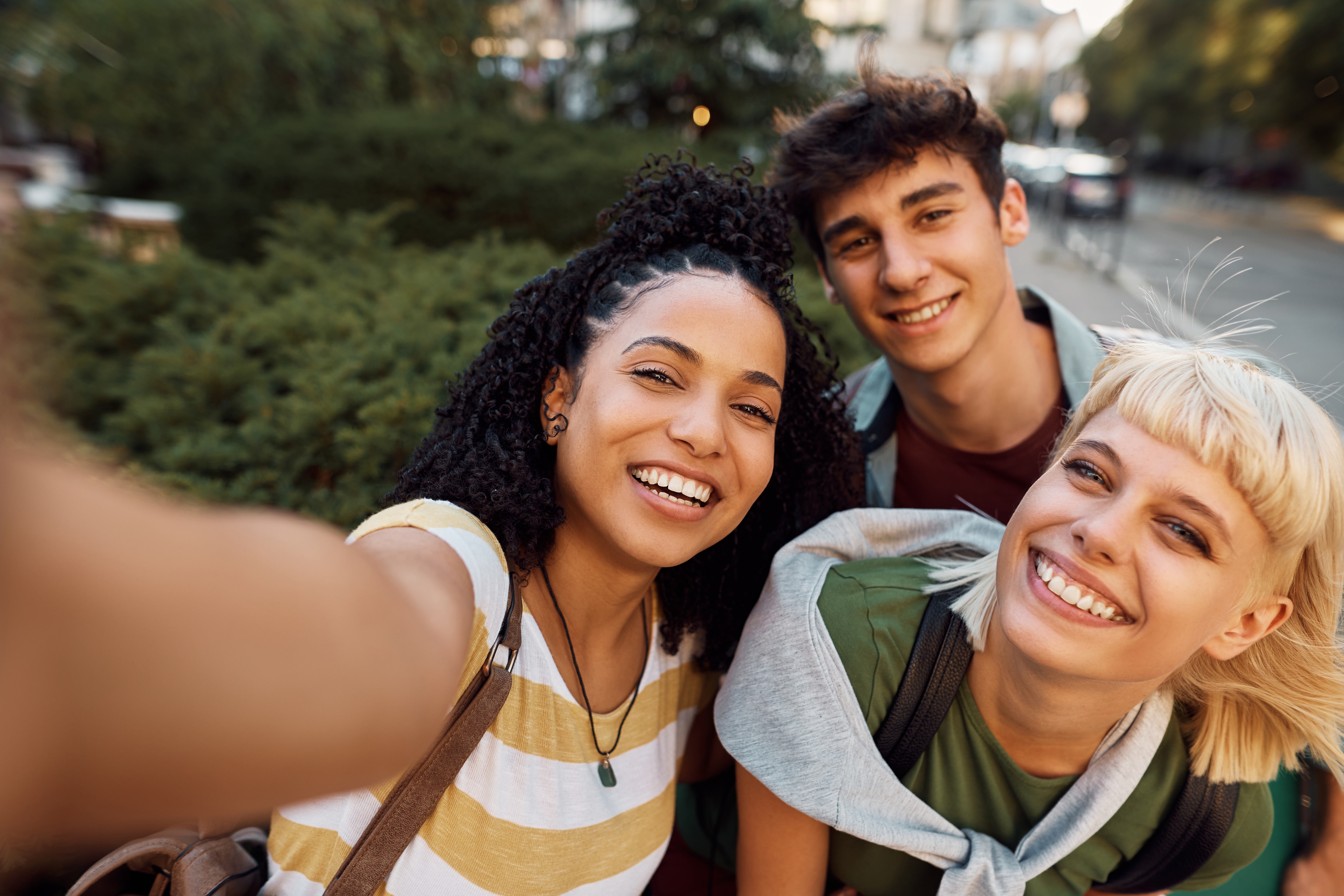 Drei Personen stehen eng beieinander und lachen in die Kamera.
