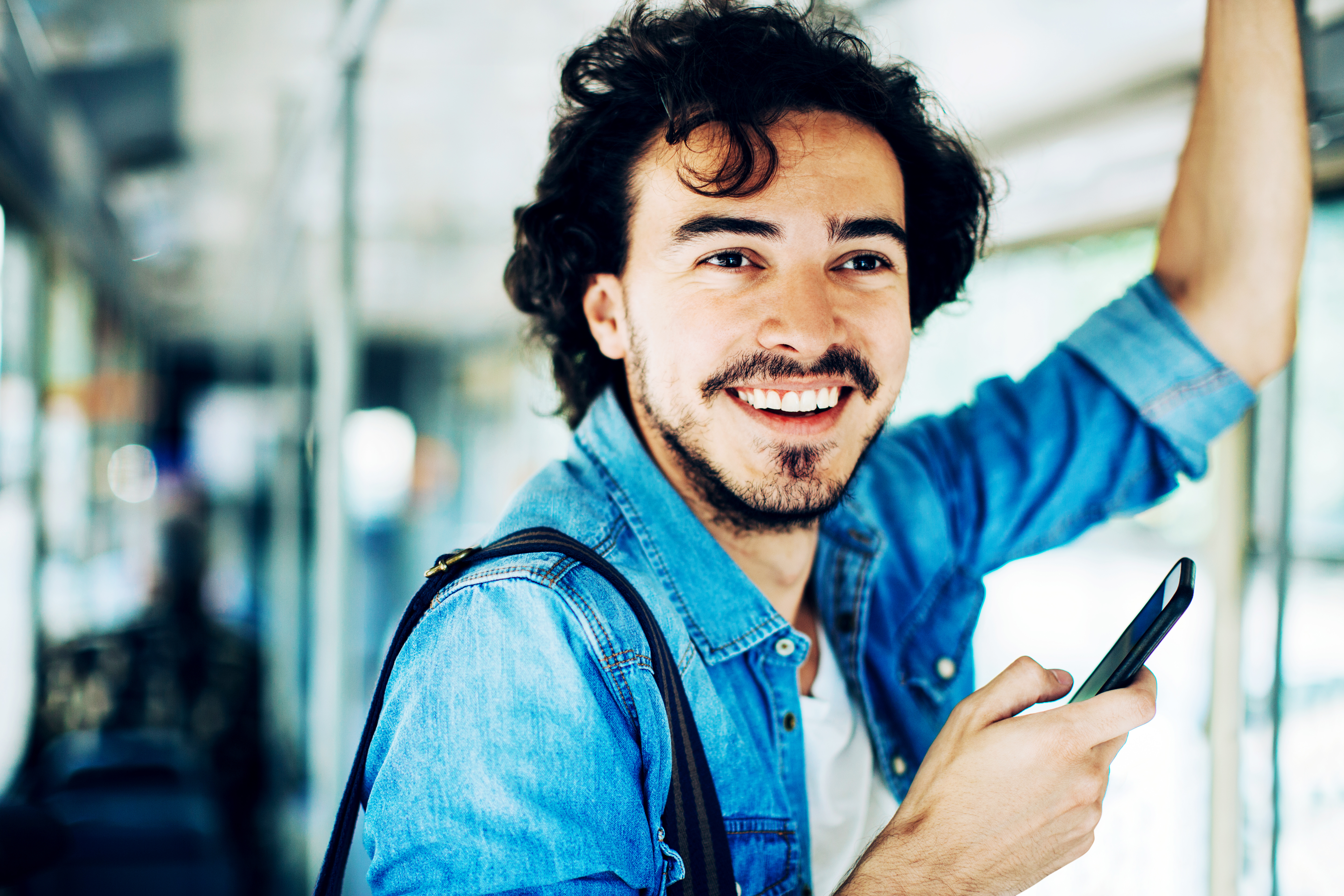 Mann steht mit Handy in der Bahn
