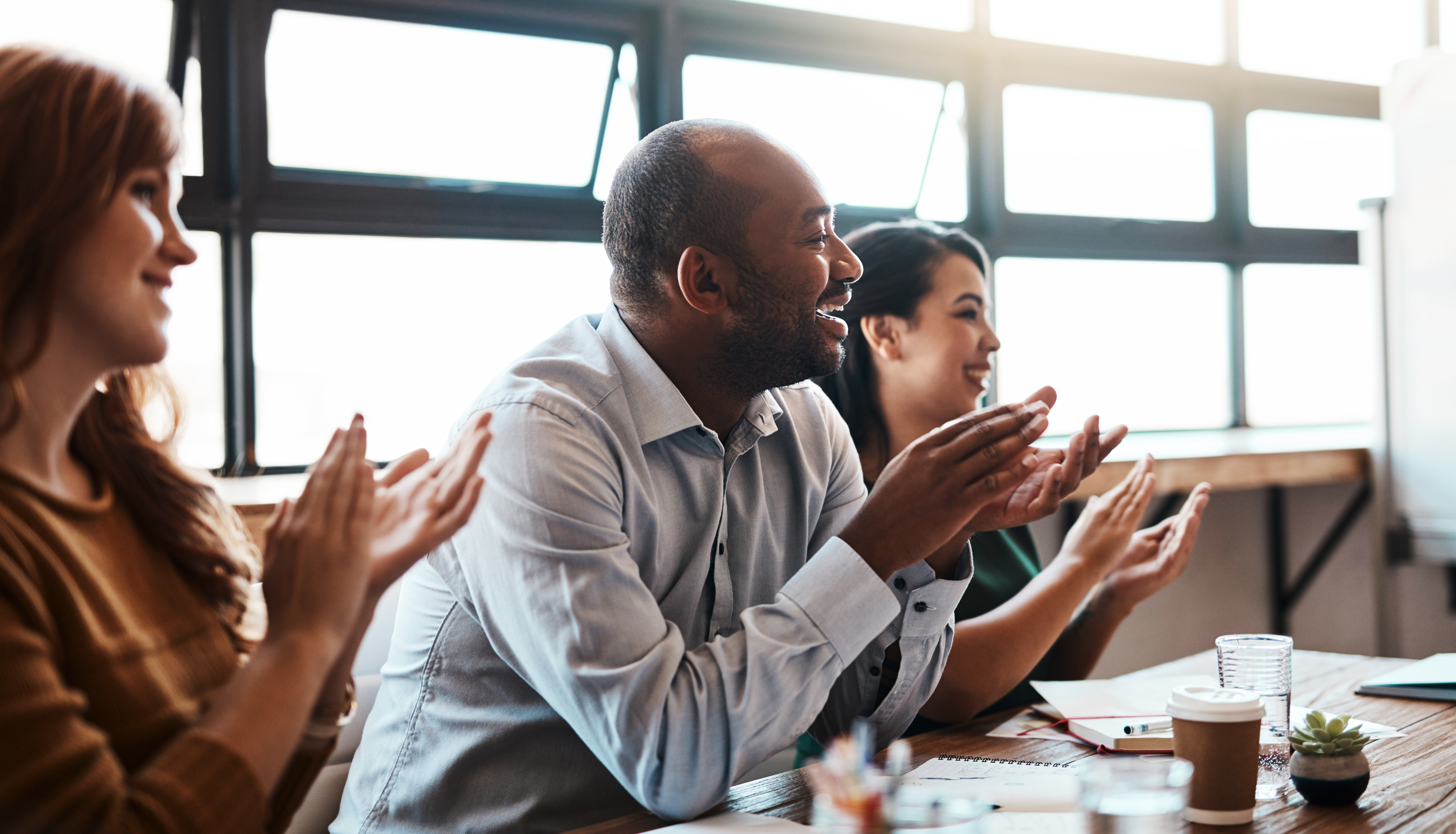 Mehrere Personen sitzen am Tisch zusammen und applaudieren.