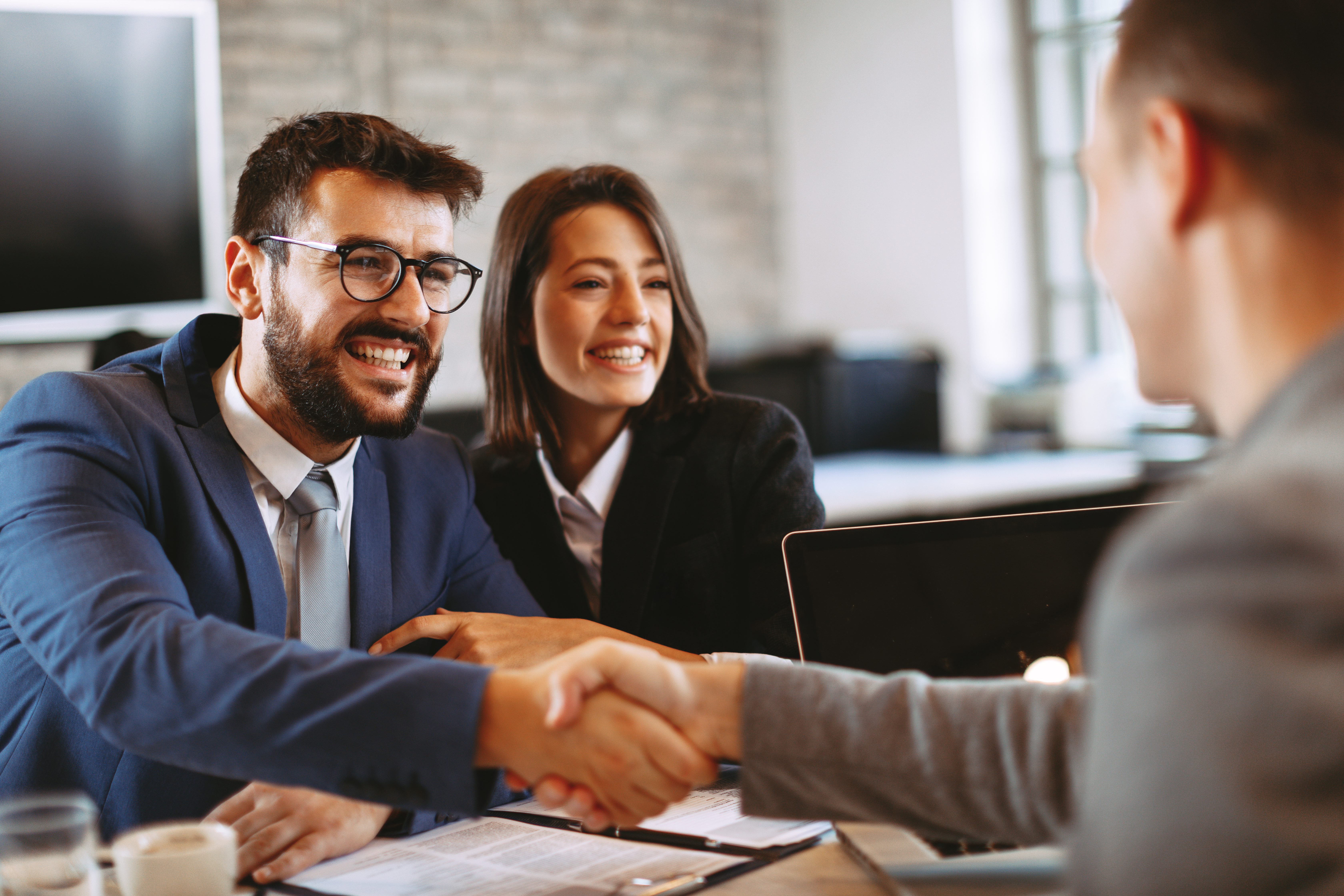 Zwei Männer geben sich über einen Tisch hinweg die Hand.