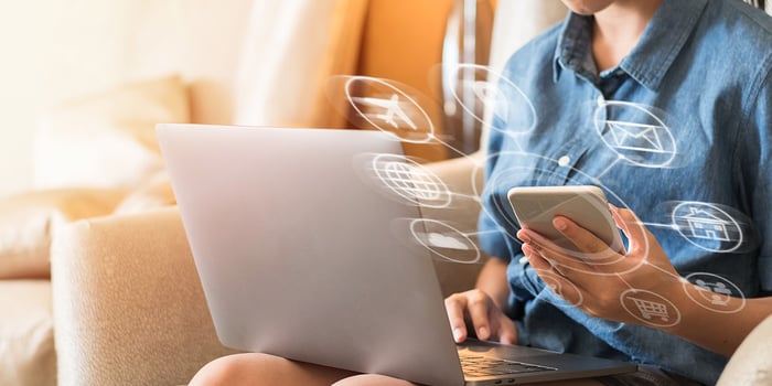 a person sitting on a couch using a laptop and a phone