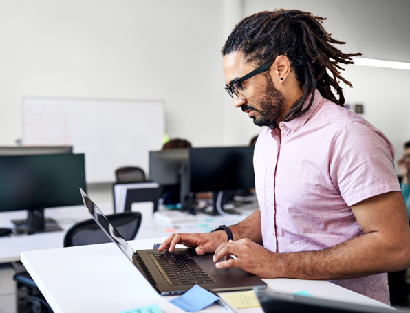 Sqre|Man standing while working on his laptop