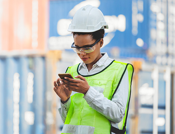 Sqre|Woman in reflective vest and white hard hat reviewing her smartphone