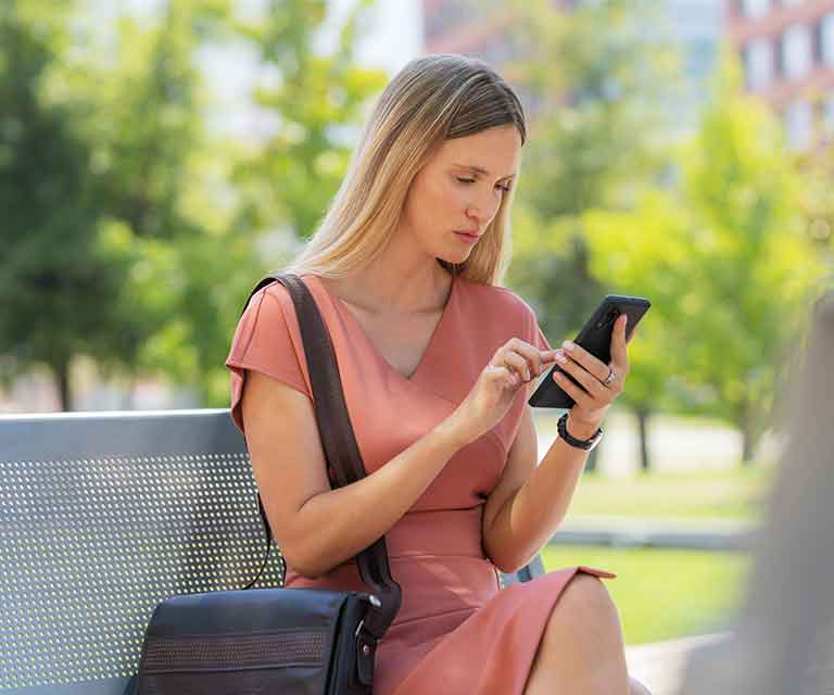 Tile|Woman in a park using her cell phone