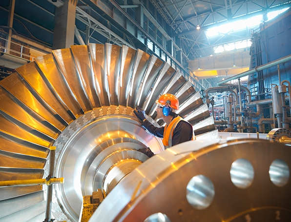 Man wearing hard hat in manufacturing facility touching machinery