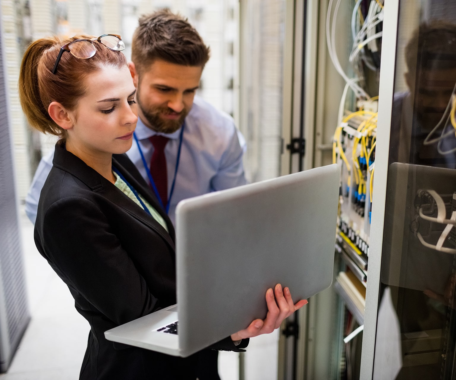 Tile | Two people looking at a laptop in a data center