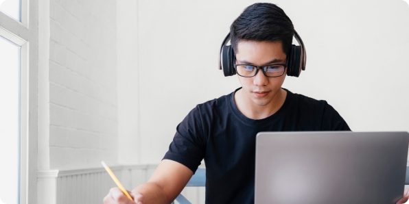 Tile | Young male student studying at home using a laptop