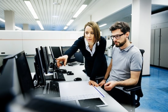 Tile | Two professionals at a desk looking at a monitor