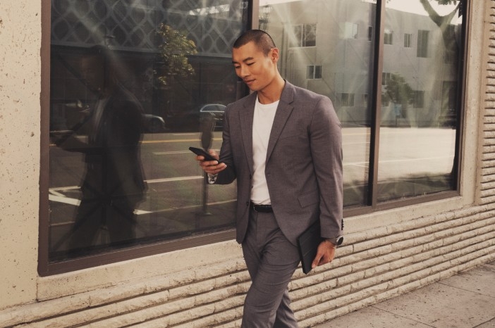 Tile|Businessman walking down the street, looking at his smartphone