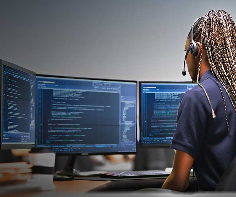 Tile | Woman sitting in front of multiple monitors