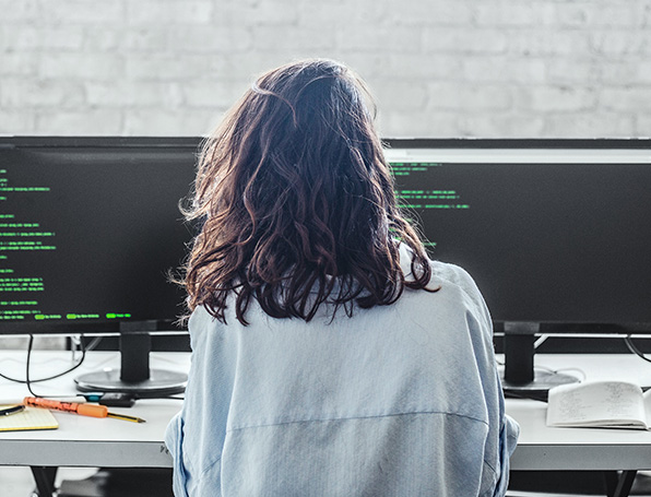 Sqre|Woman sitting at a desk looking at two monitors