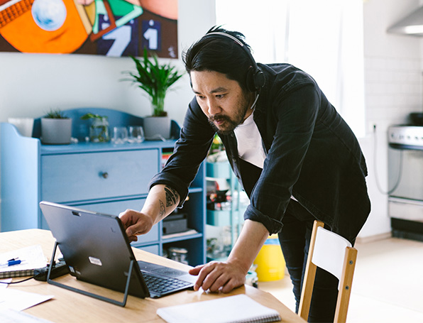 Sqre|Man standing over a table using a laptop