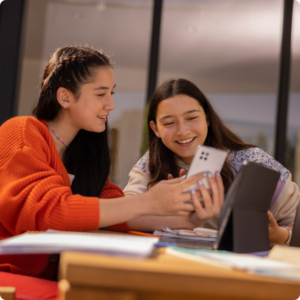 Sqre | Two female students looking at mobile phone and laptop