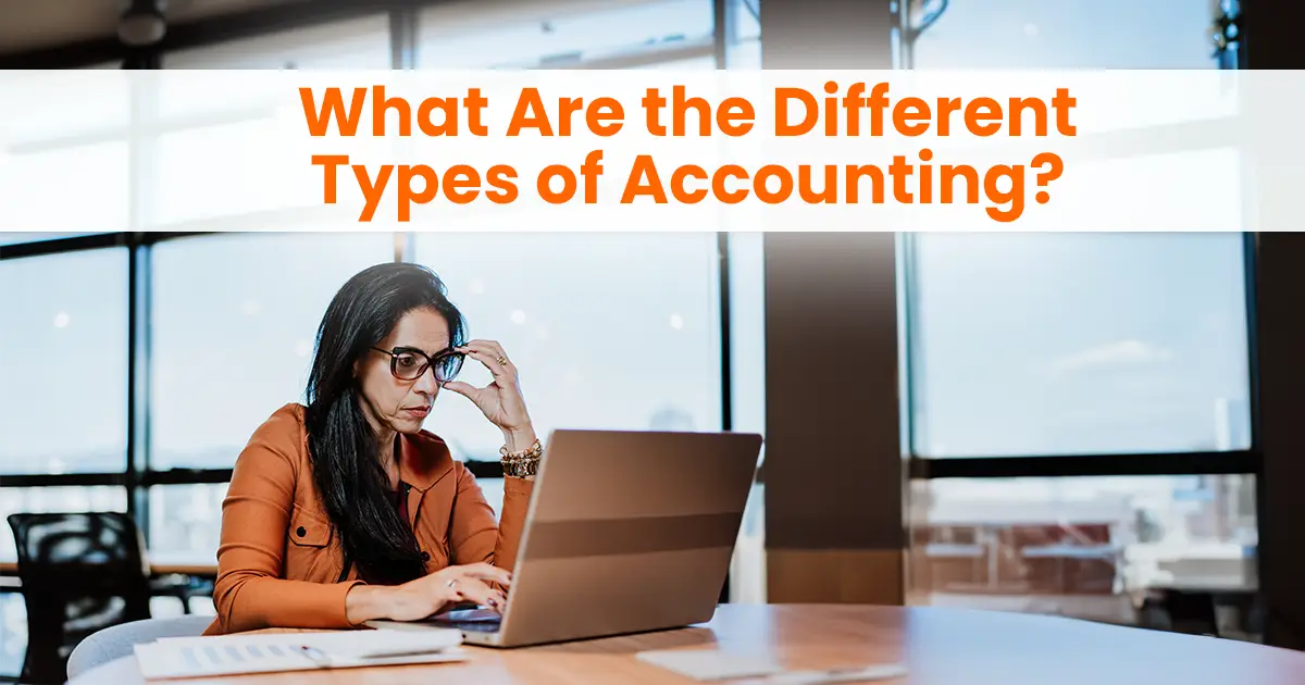 A woman in glasses sits at a table in a bright office, looking at her laptop with a focused expression, with text overhead reading "what are the different types of accounting?.