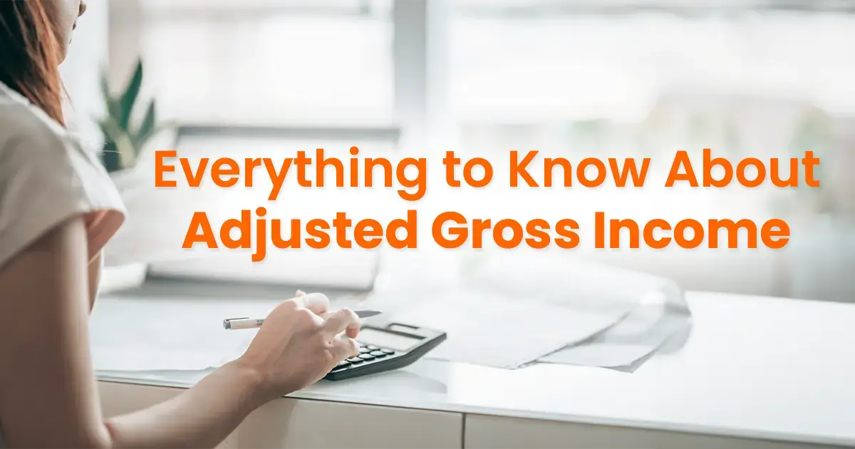 Woman seated at a desk calculating finances with a calculator, with the text "everything to know about adjusted gross income" overlaying the image.