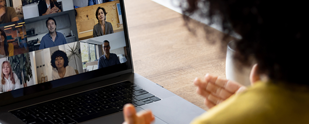 A woman is on a laptop with a group of people on a video conference.