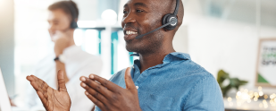 A man in a headset is talking to a customer in a call center.