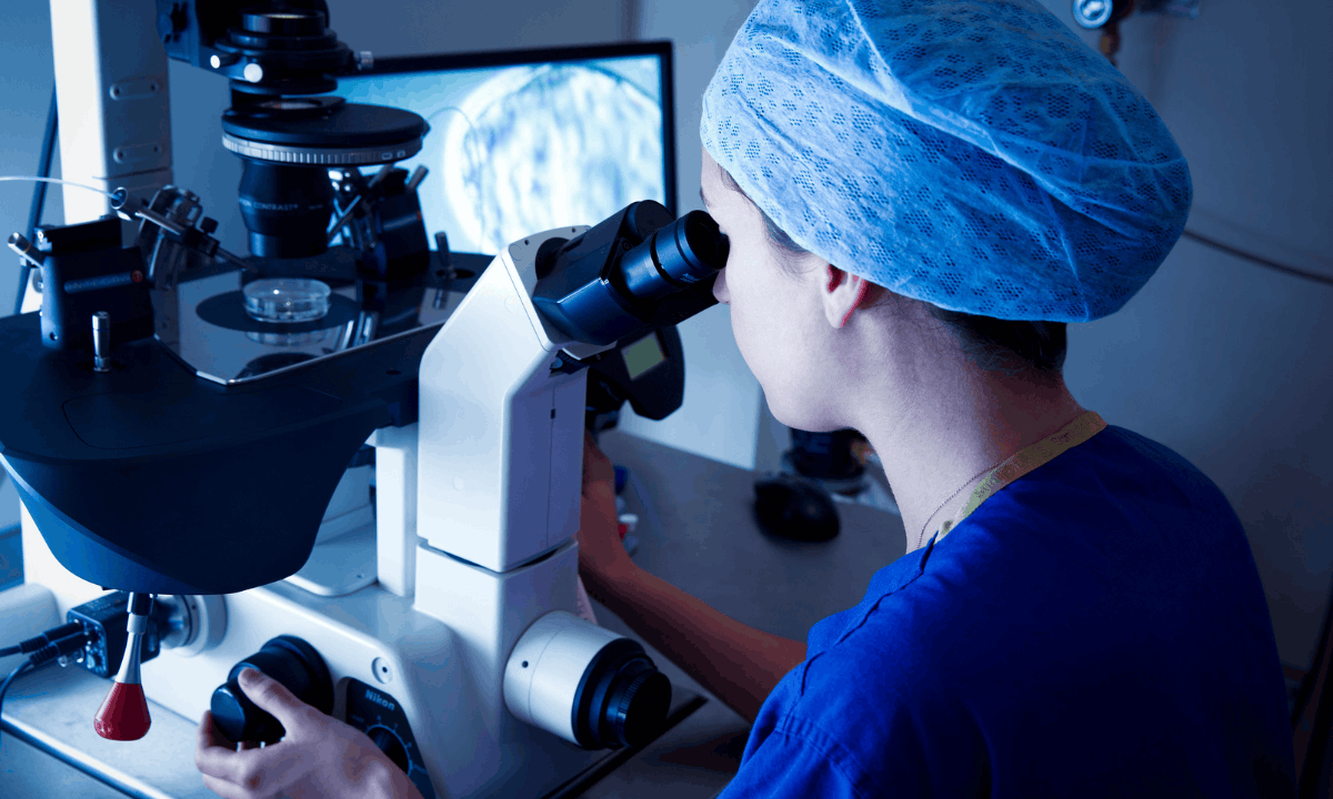 image of an embryologist using microscope
