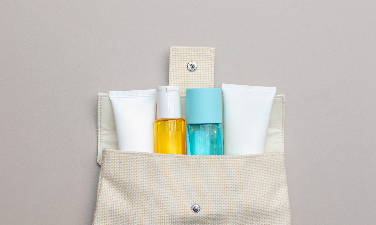A set of travel-sized hair care products, including shampoo and conditioner bottles, organized inside a beige cosmetic bag
