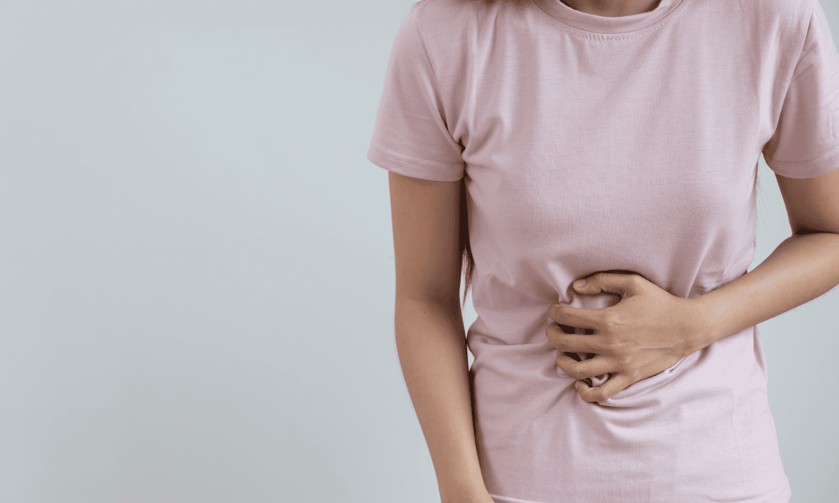 Woman holding her abdomen in discomfort due to stomach cramping or bloating. 