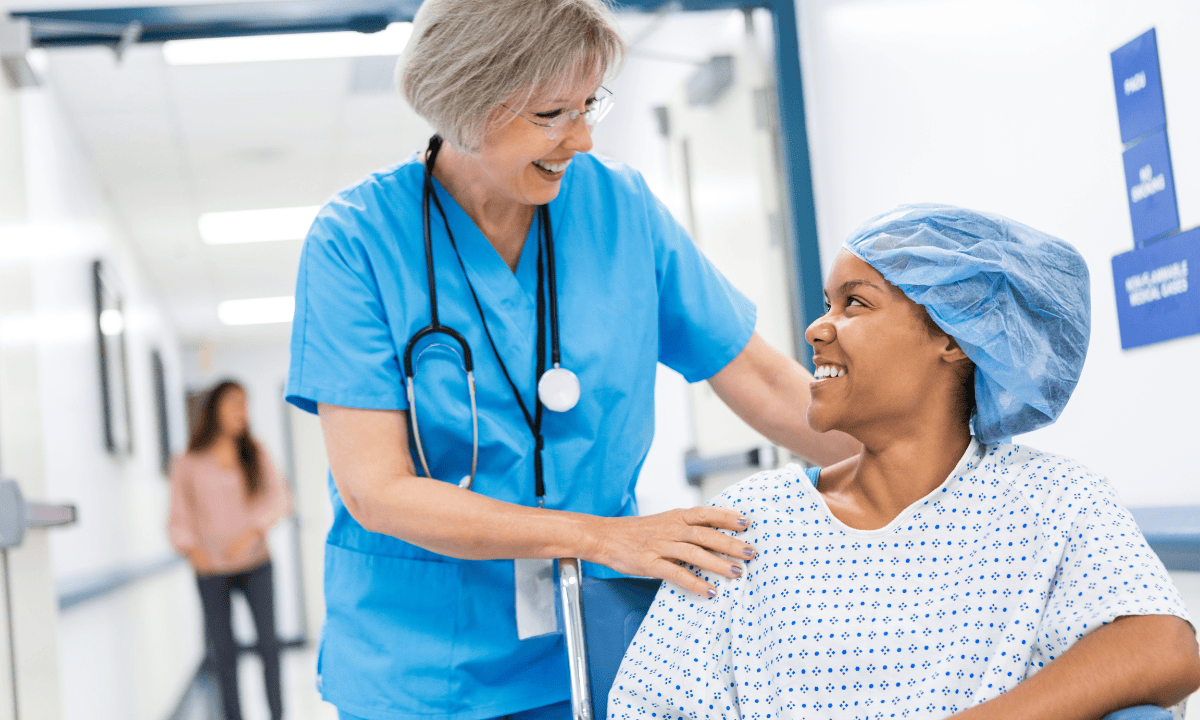 A nurse smiling with a patient on wheelchair