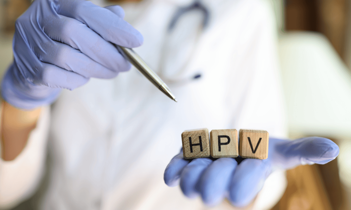 Doctor in blue gloves holding wooden blocks spelling HPV