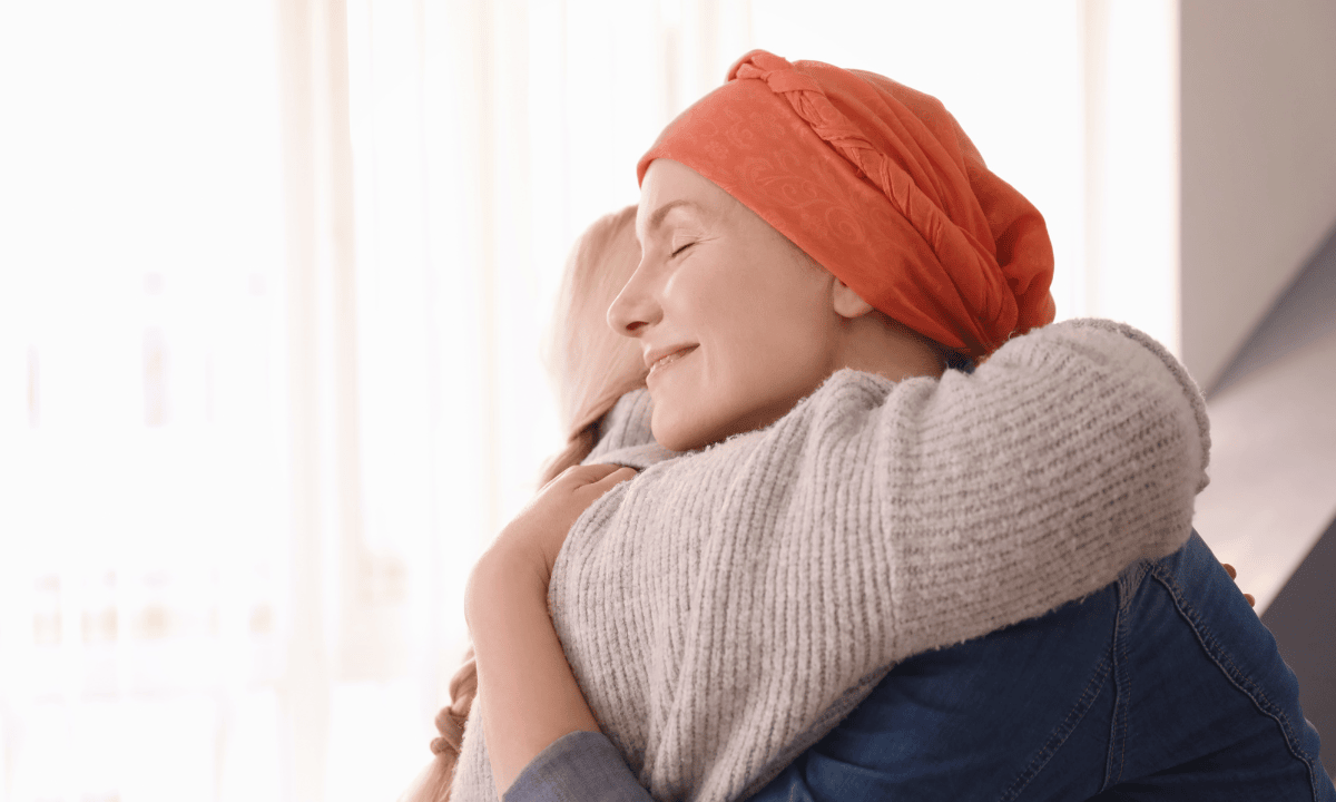 A cancer patient smiling and hugging another person