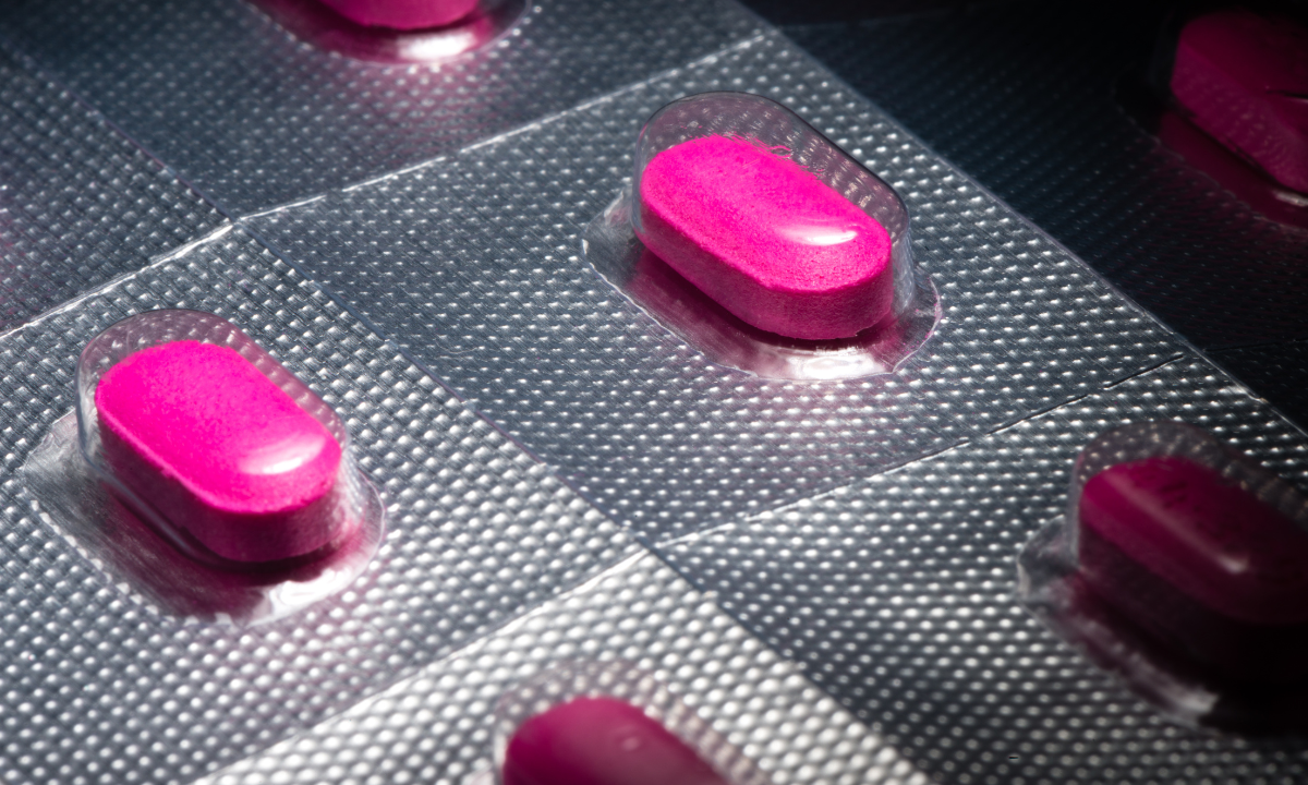 Close-up view of bright pink antihistamine tablets encased in a silver foil blister pack.