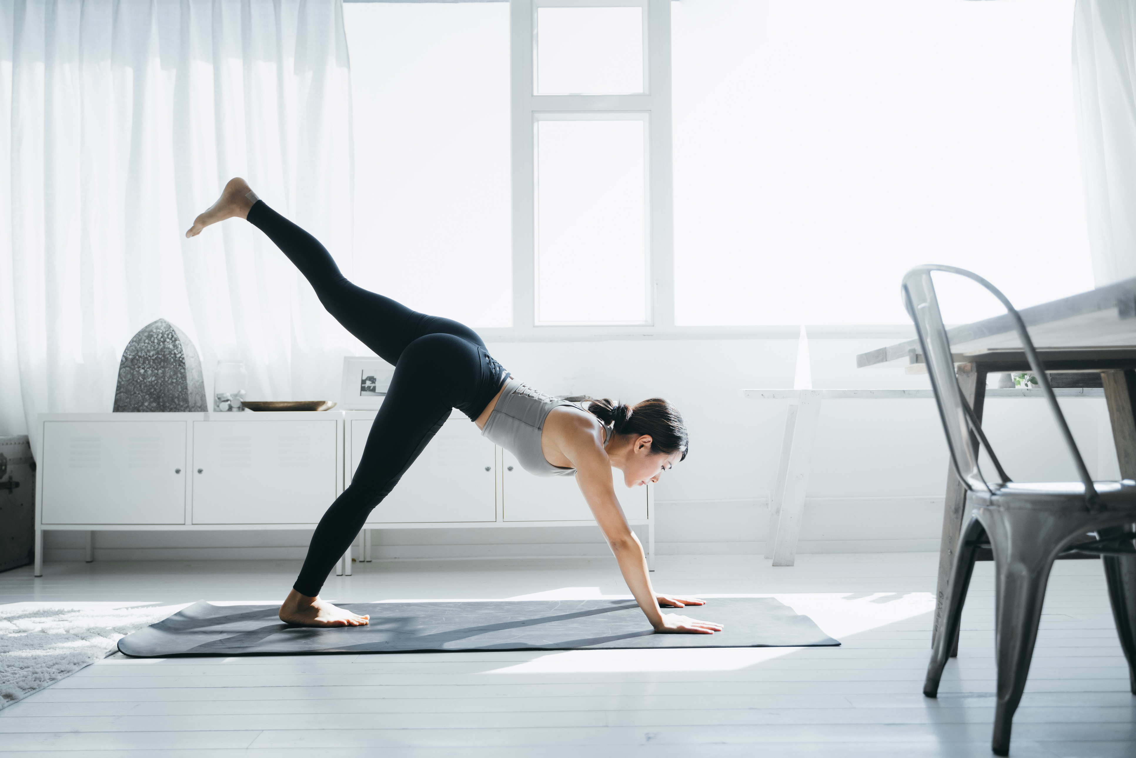 Young woman doing yoga exercise at home on a mat potentially avoiding shoulder and elbow injury orthopaedics case